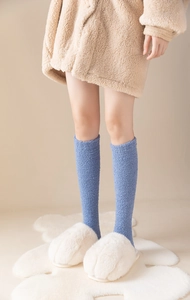 Detail of blue coral fleece knee high socks worn with white paw slippers for home comfort