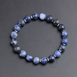 Men's natural blue sodalite bead bracelet with cylindrical dark metal spacers on dark background