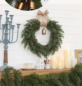 Close-up of Christmas wreath with natural pine cones, burlap bow, and a golden bell