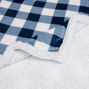 Detailed view of blue plaid flannel fabric and soft white sherpa fleece lining on blanket