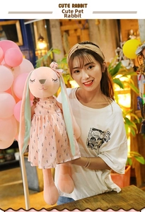 Detail of cute plush rabbit in floral dress held by model in warm cozy room