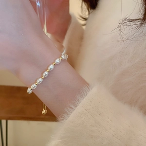 Detailed view of adjustable pearl bracelet with gold beads on a woman's wrist