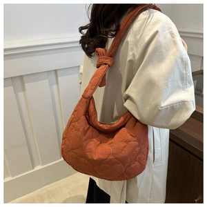 Quilted heart pattern tote bag in orange-red with knot detail shown on model shoulder