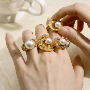 Detail of luxury gold-plated pearl rings with crystals and Greek meander patterns