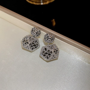 Macro shot of silver floral hollow hexagonal earrings with vintage granulation texture