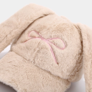 Close-up of pink bow embroidery and fuzzy texture on a beige plush bunny ear baseball cap