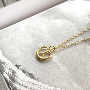 Macro shot of 925 sterling silver pretzel pendant necklace with polished gold finish