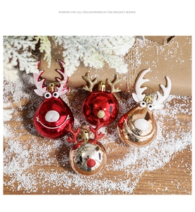Detail of red and gold reindeer Christmas balls on snow-covered wood with holiday ornaments