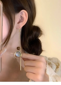 Close-up of vintage tassel earrings with wooden beads and shell charms on model