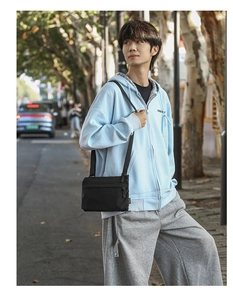 City street view of a black lightweight nylon crossbody bag with durable fabric strap