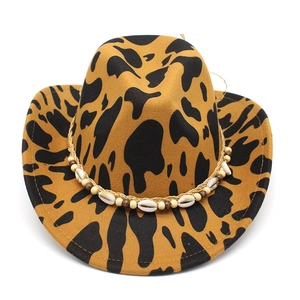Detail of western fedora hat featuring cow print pattern and shell beaded decorative band