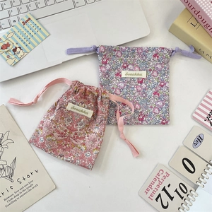 Detailed flat lay of floral drawstring pouches in pink and blue on a minimalist desk