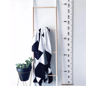 Nordic canvas growth chart for kids with black and white geometric pattern hanging on a ladder