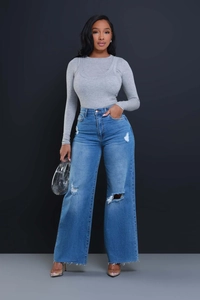 Detail of high-waisted distressed wide-leg jeans with ripped knees and raw hems