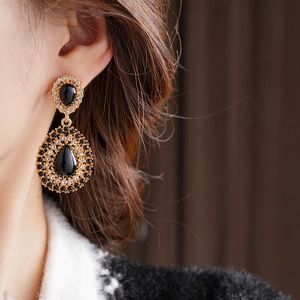 Gros plan de boucles d'oreilles vintage en or avec pendentifs gouttes noires et cristaux