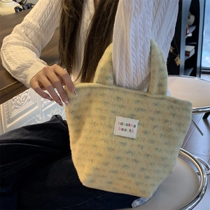 Close-up of fluffy yellow plush tote bag showing the sozakka beauté label and soft texture