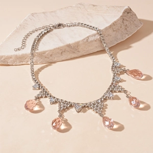 Close-up of pink teardrop crystal necklace with silver rhinestone chain on a stone