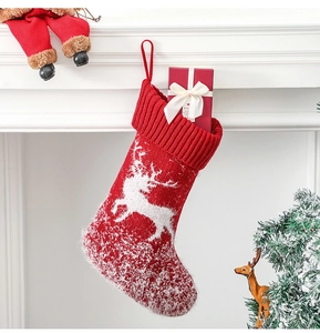 Close-up of a red knitted Christmas stocking with reindeer pattern hanging on a white mantel