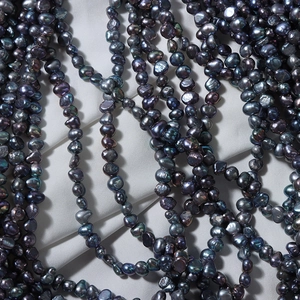 Baroque irregular dark pearls with metallic luster on gray fabric background