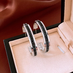 Macro detail of silver C-shaped hoop earrings with black rectangular crystals in a gift box