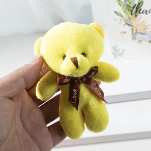 Close-up of a small yellow plush teddy bear keychain with a Love printed silk ribbon