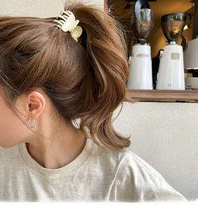 Dettaglio della pinza per capelli bianco crema e orecchini a cerchio in argento