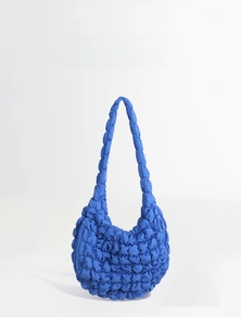 Detail view showing textured bubble pleats on a bright blue cloud shoulder bag
