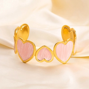 Detailed view of pink enamel heart on 18K gold plated stainless steel open bangle