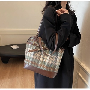Model wearing a vintage plaid tote bag with brown leather trim and metal buckle detail