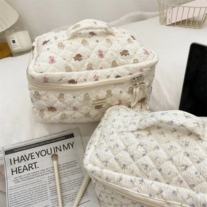 Detail of cute bear and floral pattern on beige quilted fabric makeup bag with zipper