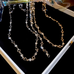 Close-up of gold and silver heart-shaped tassel necklaces with rhinestones in a box