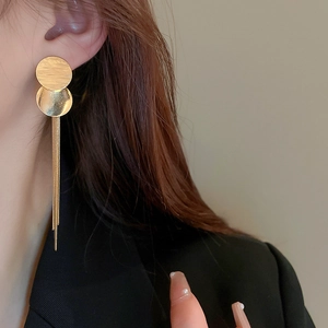 Primo piano di eleganti orecchini a nappa dorati con paillettes indossati da una modella