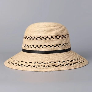 Detailed view of raffia sun hat featuring three-tier hollow weave and black ribbon band