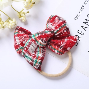 Detail of red and green plaid Christmas bow headband with soft nude nylon band