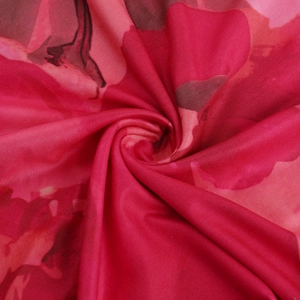 Macro d'un tissu rouge à motifs floraux montrant la texture soyeuse et la fluidité