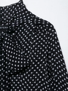 Detail of black polka dot chiffon cape blouse with elegant bow tie neckline and soft texture