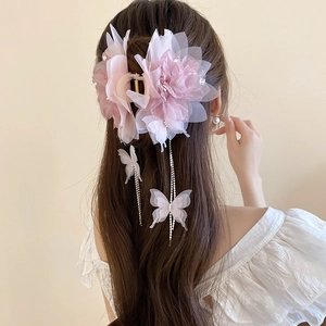 Detail showing a pink mesh flower hair claw with butterfly tassel on brown long hair