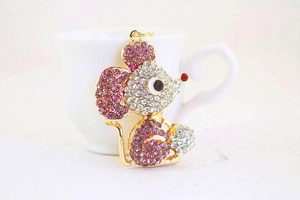Close-up of golden mouse keychain with white and pink crystal rhinestones detail