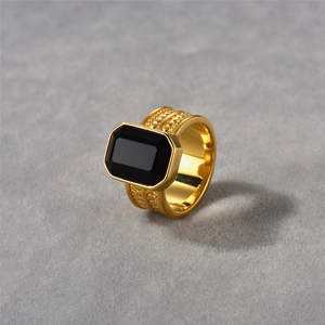 Detalle de anillo chapado en oro de 18k con ónix negro sobre fondo de terciopelo gris