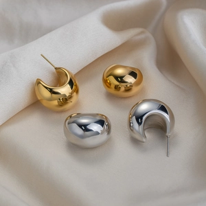 Polished gold and silver C-shaped chunky hoop earrings set on silk fabric