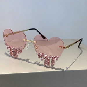 Detail of pink heart-shaped sunglasses with teardrop crystals on a minimal gold frame