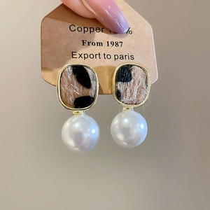 Close-up of vintage leopard print geometric earrings with large pearl drop accents