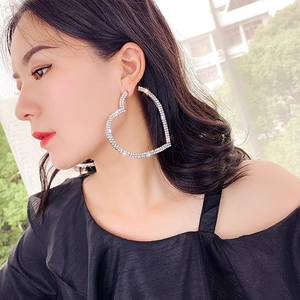 Détail de grandes boucles d'oreilles cœur serties de strass portées par un mannequin