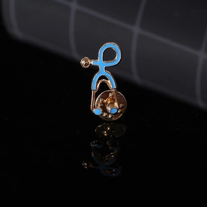 Macro shot of blue enamel stethoscope brooch with gold metal plating on reflective base