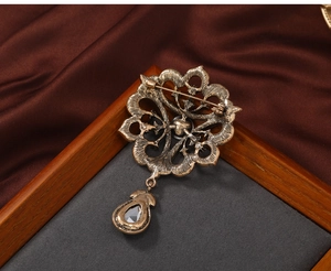 Macro view of vintage gold hollow brooch back featuring horizontal pin and crystal teardrop