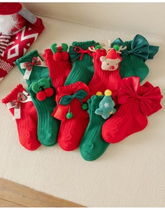 Close-up of red Christmas socks with 3D bows, cherry, and reindeer head ornaments