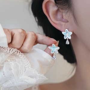 Nahaufnahme von Stern-Ohrstecker mit blauem Opal und Zirkonia-Tropfen am Model