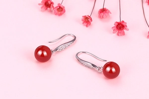Macro detail of red chalcedony bead earrings with silver hooks and sparkling zircon accents