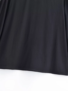 Detail of a black long-sleeve shirt showing the smooth hemline and high-quality stitching