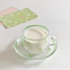 Detailed close-up of lily of the valley glass cup and saucer set with green edging